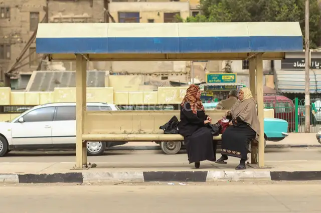 Two Women Sitting and Waiting for the Bus at a Station in Cairo