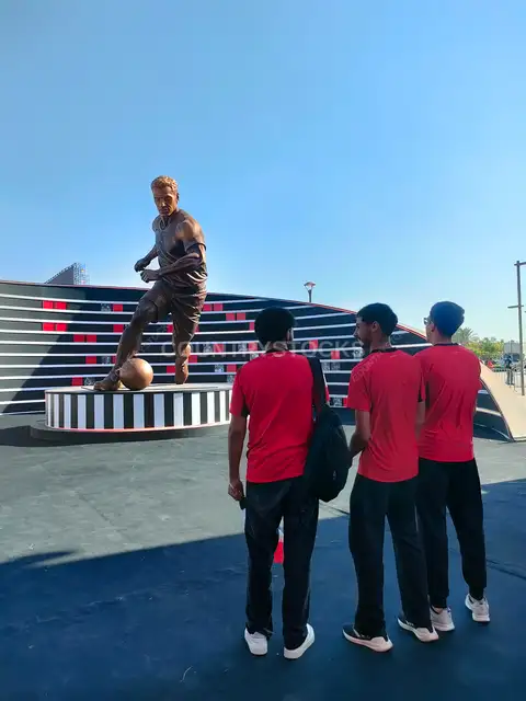 Young Fans View Football Player Statue at Fan Zone