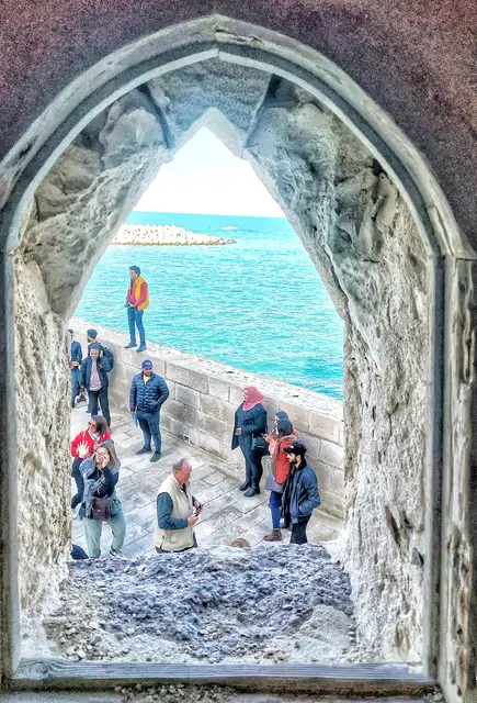 Tourists at Qaitbay Citadel Sea Wall Through Stone Arch