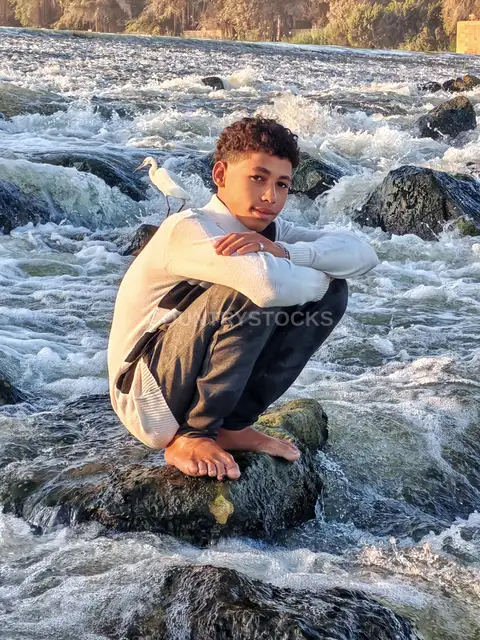 Young Man Sitting on Rock at Al-Qanater Al-Khayreya Rapids