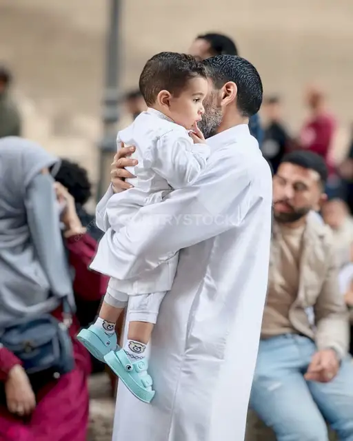 Father Carrying His Son in White Jalabeyas for Eid Prayer