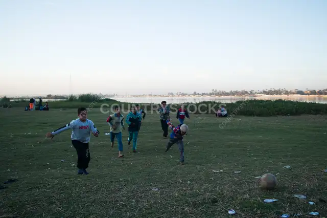 Children Chasing the Ball on an Open Football Field