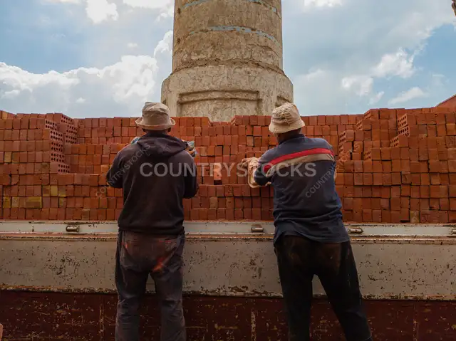 Two Egyptian Workers Unloading Red Bricks Outdoors
