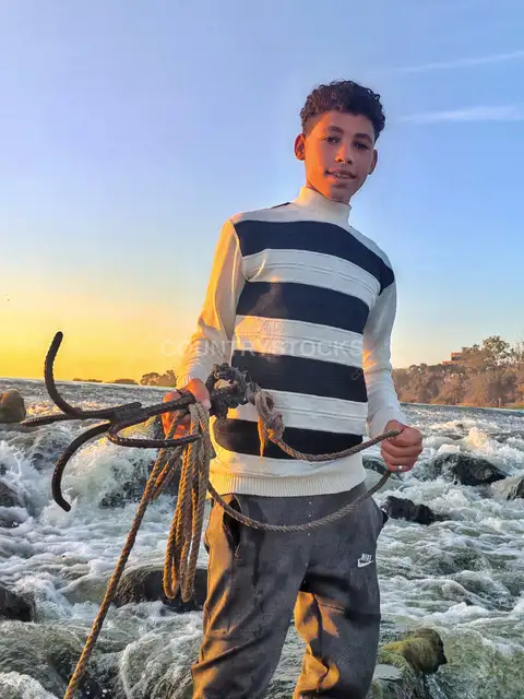 Young Man Holding Fishing Hook at Al-Qanater Waterfalls