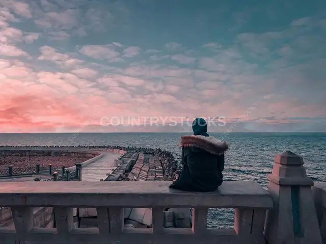 Person Sitting on Seafront Railing at Sunset, Alexandria