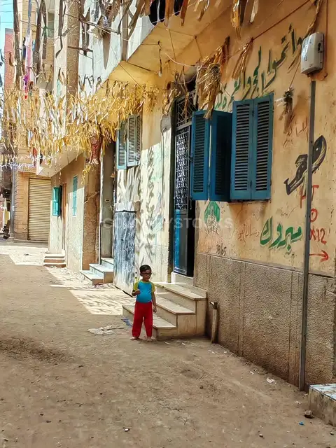 Little Boy in a Village Alley with Traditional Hajj Decorations