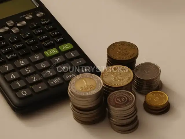 Egyptian Coins and Scientific Calculator on White Surface