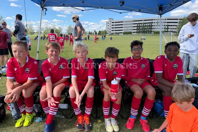 Youth Soccer Team Resting on Sideline During Tournament
