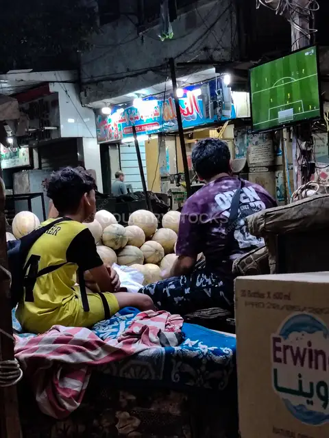 Cairo Market Vendor Watches Football Match at Night