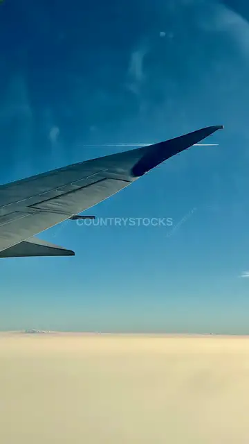 Airplane Wing View Above Clouds from Passenger Window