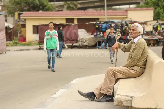 رجل مسن بعصاية جالس في شارع القاهرة