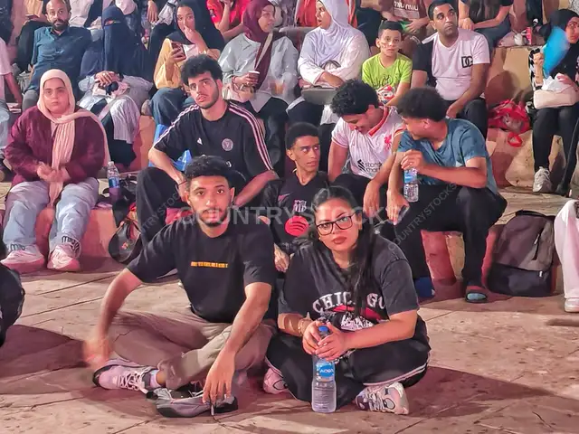 شباب مصريون يجلسون معاً في انتظار فعالية خارجية