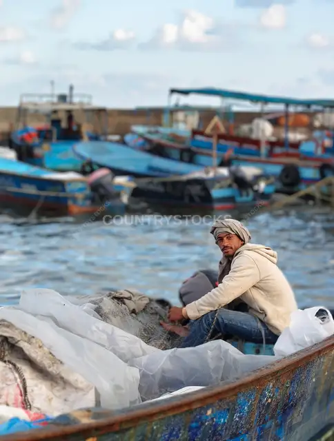 صياد يغزل الشبك على مركب في المكس الإسكندرية