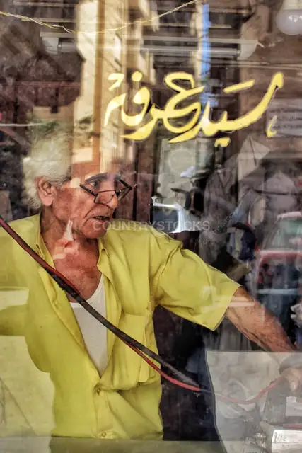 خياط سيد عرفة يكوي الملابس خلف زجاج المحل، الإسكندرية