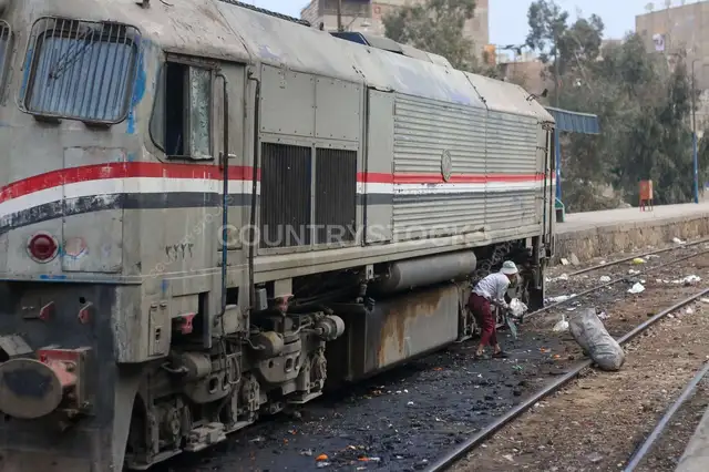 عامل سكة حديد بينظف القضبان بجانب قطار في القاهرة