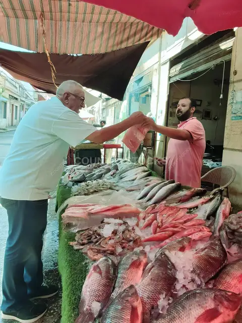 بائع سمك وزبون في حلقة سمك السيدة زينب بالقاهرة