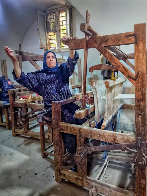 امرأة مصرية على نول خشبي تقليدي في مركز ويصا واصف بالحرانية
