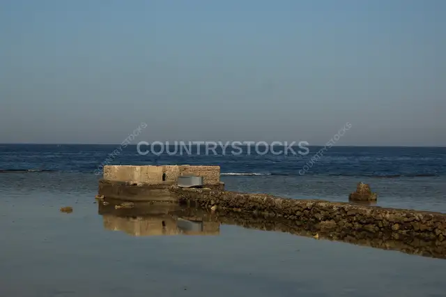 Ancient Stone Pier Ruins Reflecting in Calm Sea