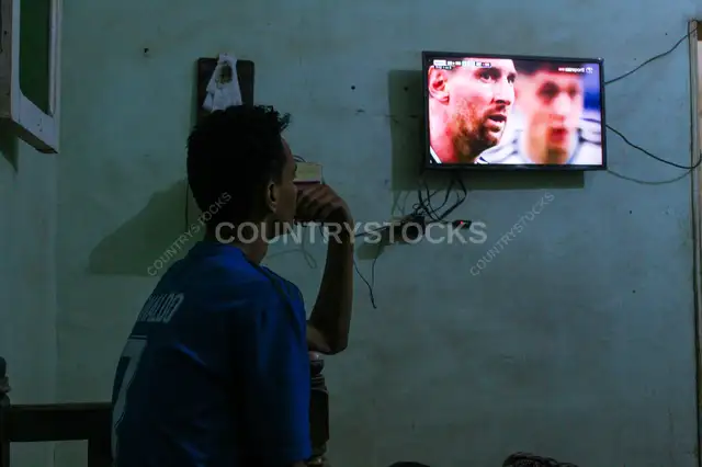 Football Fan Watching a Match on Television at Home