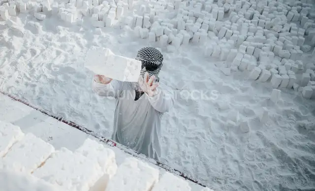 عامل محجر يرفع كتلة حجر أبيض، المنيا