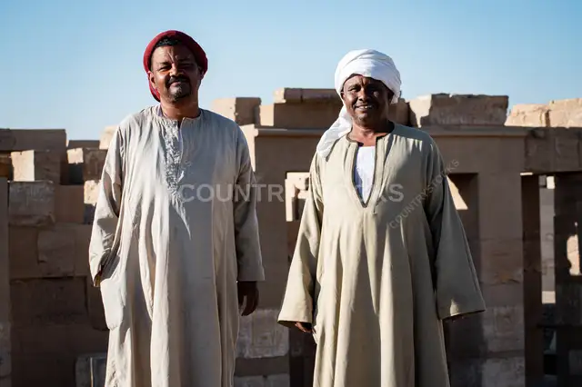 رجلان نوبيان أمام أطلال معبد أثري في أسوان