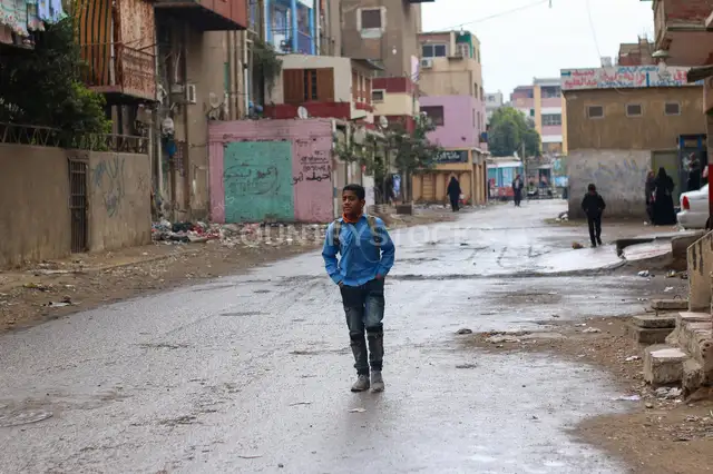 طالب مدرسة ماشي في شارع مبلول بالقاهرة