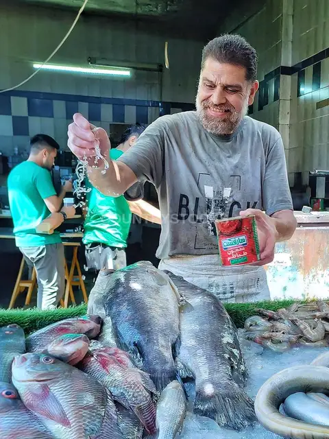 بائع سمك مصري بيرش ميه على السمك الطازج في سوق السيدة زينب