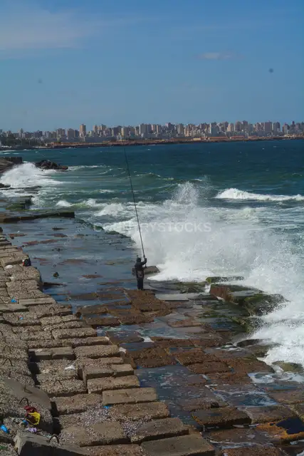 Fisherman Casting Rod on Alexandria Rocky Waterfront