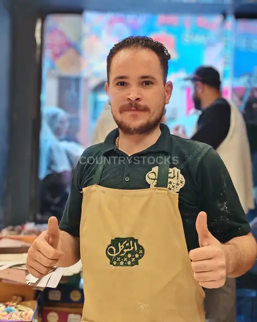 بائع محل حلوى بين الحارات يرفع إبهاميه بالقاهرة