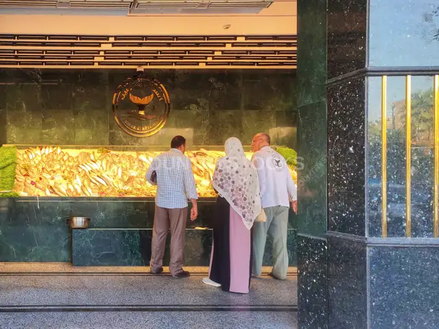 زبائن يختارون السمك الطازج من عرض مطعم الأكرمين