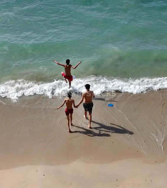 Kids Jumping Into Mediterranean Waves at Beach