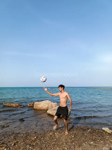 شاب يلعب كرة القدم على شاطئ البحر الأحمر في الغردقة