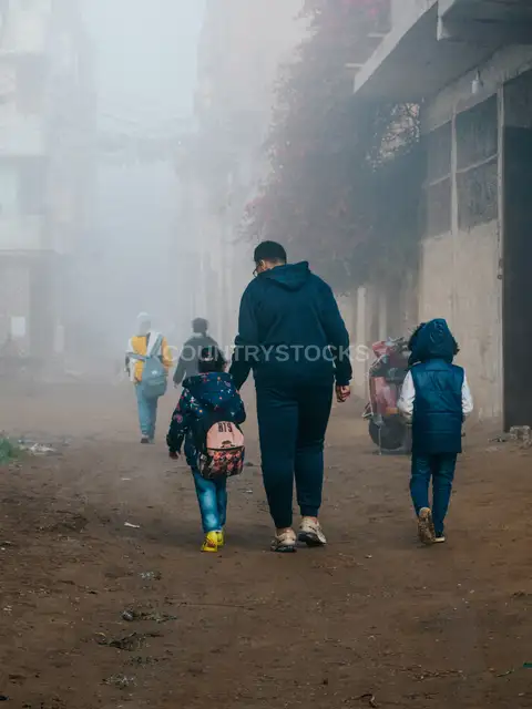 أب يصطحب أطفاله إلى المدرسة في صباح ضبابي