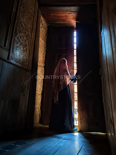 امرأة محجبة تفتح نافذة خشبية أثرية في مجمع السلطان قلاوون