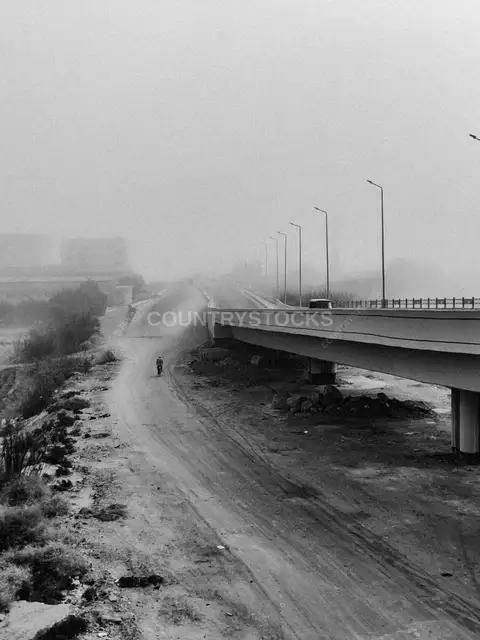 Cyclist on Dirt Road Beside Elevated Bridge, Egypt