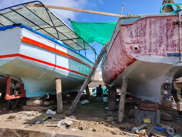 رجل يجلس بين مراكب خشبية في راس التين الإسكندرية