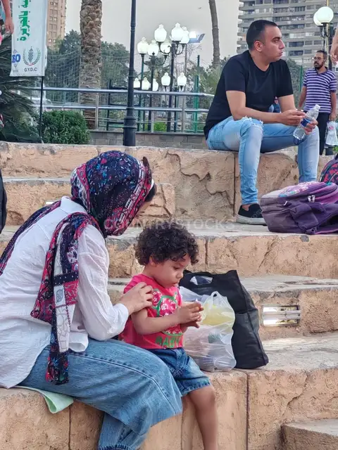 أم تُطعم طفلها قبل انطلاق مباراة كأس العالم في مركز شباب الجزيرة
