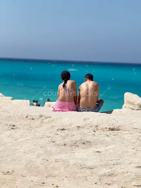 زوجان يجلسان على الشاطئ أمام البحر في الساحل الشمالي بمصر