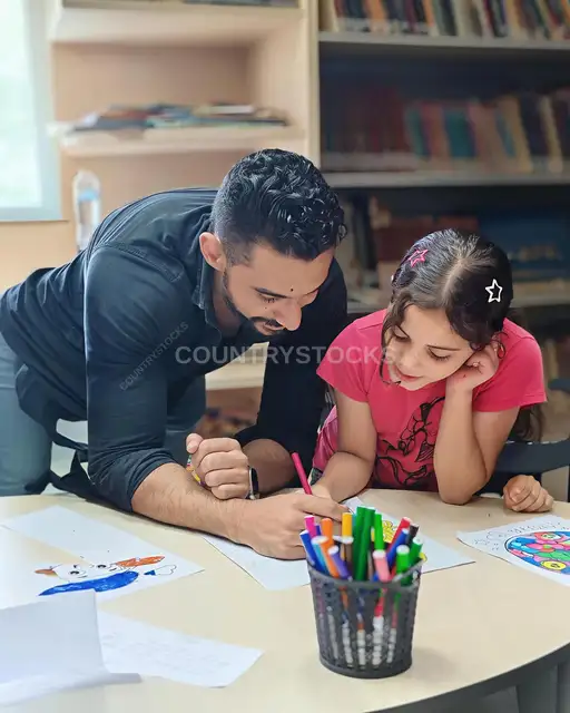 مدرب يساعد طفلة في نشاط الرسم والتلوين، مكتبة أطفال القاهرة