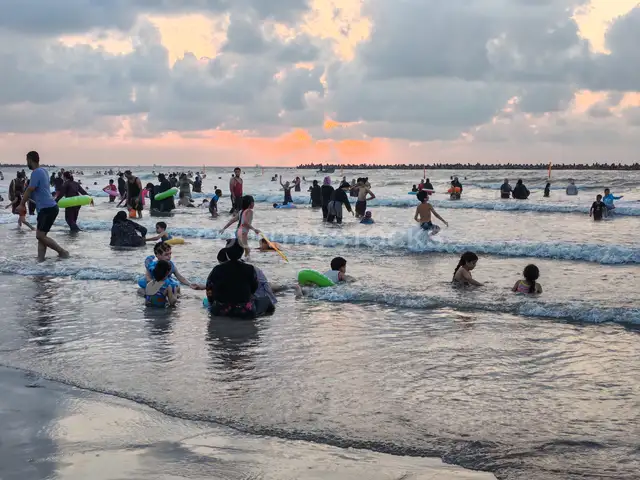 عائلات ومصطافون يسبحون على شاطئ رأس البر عند الغروب