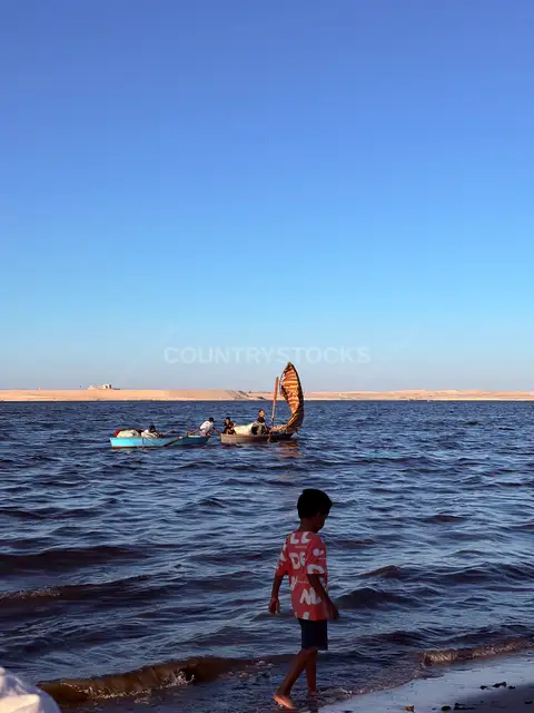 طفل وقوارب صيد على شاطئ بحيرة التمساح، الإسماعيلية