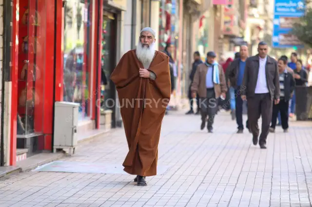 راجل كبير ماشي على رصيف زحمة في القاهرة