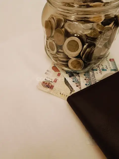 مطرطبان عملات معدنية وأوراق جنيه مصري مع محفظة