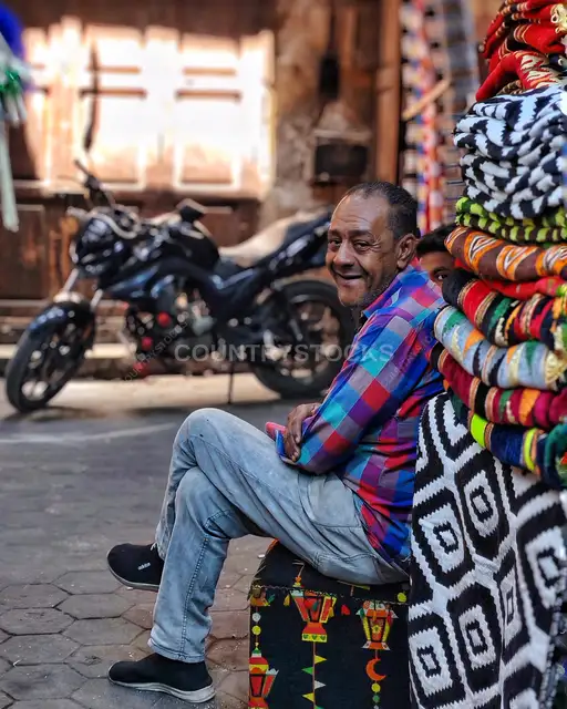 Egyptian Street Vendor Sitting by Colorful Textiles, Cairo
