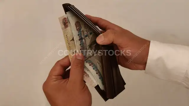 رجل يمسك محفظة بها أوراق نقدية مصرية