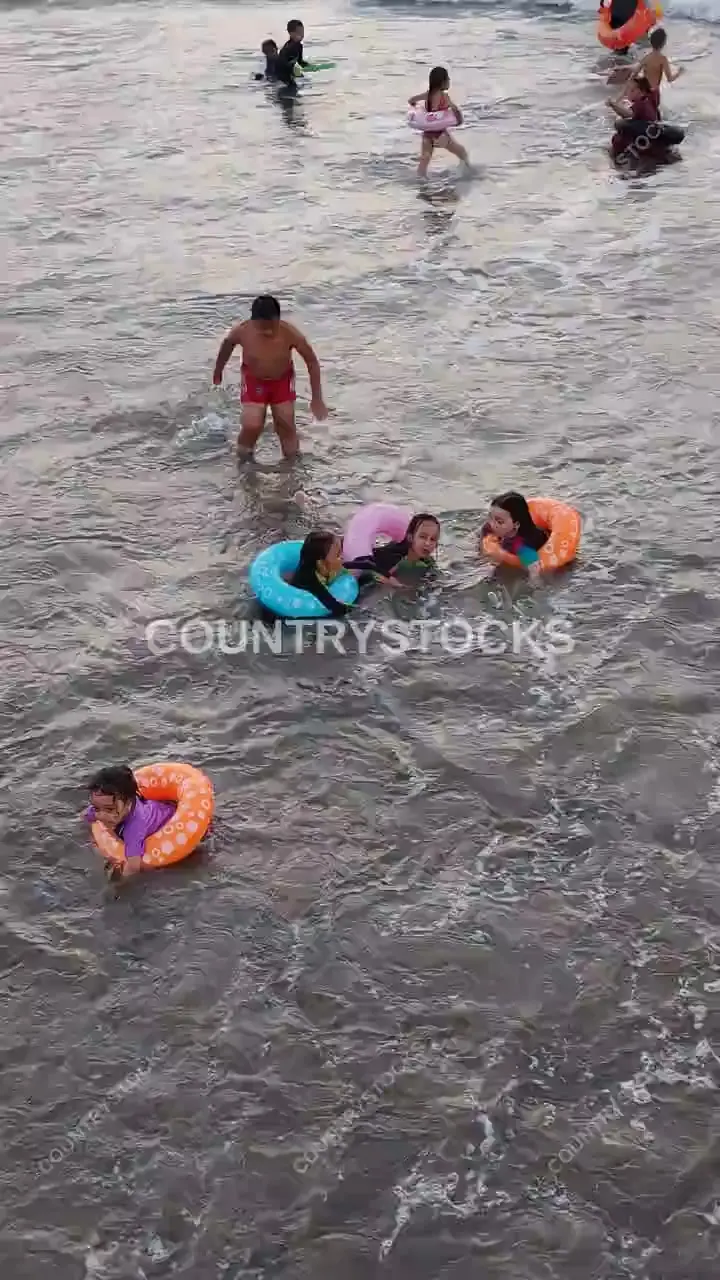 أطفال يسبحون بعوامات في شاطئ رأس البر، دمياط